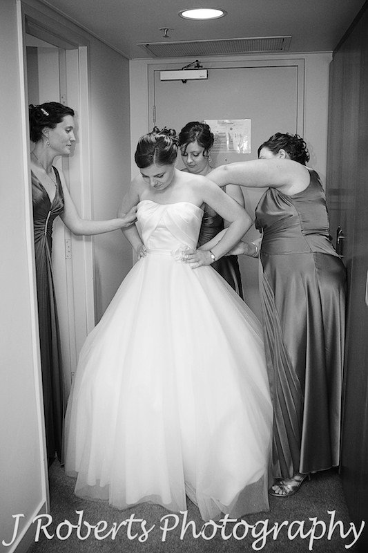 Bride having her dress done up by her bridesmaids - wedding photography sydney